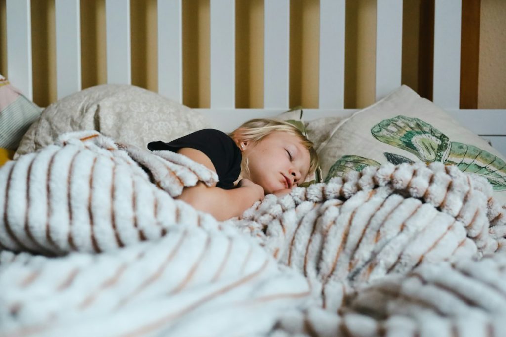 Young child asleep in bed under a blanket at bedtime