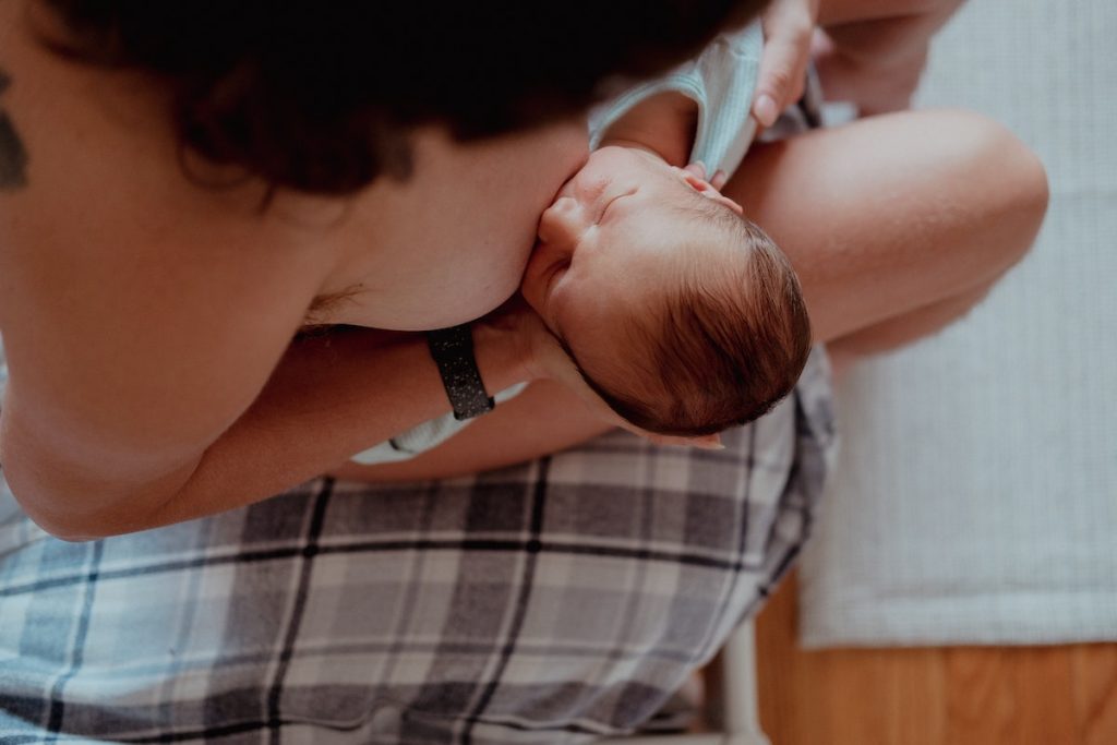 Mother holding her newborn baby while nursing in comfortable clothing