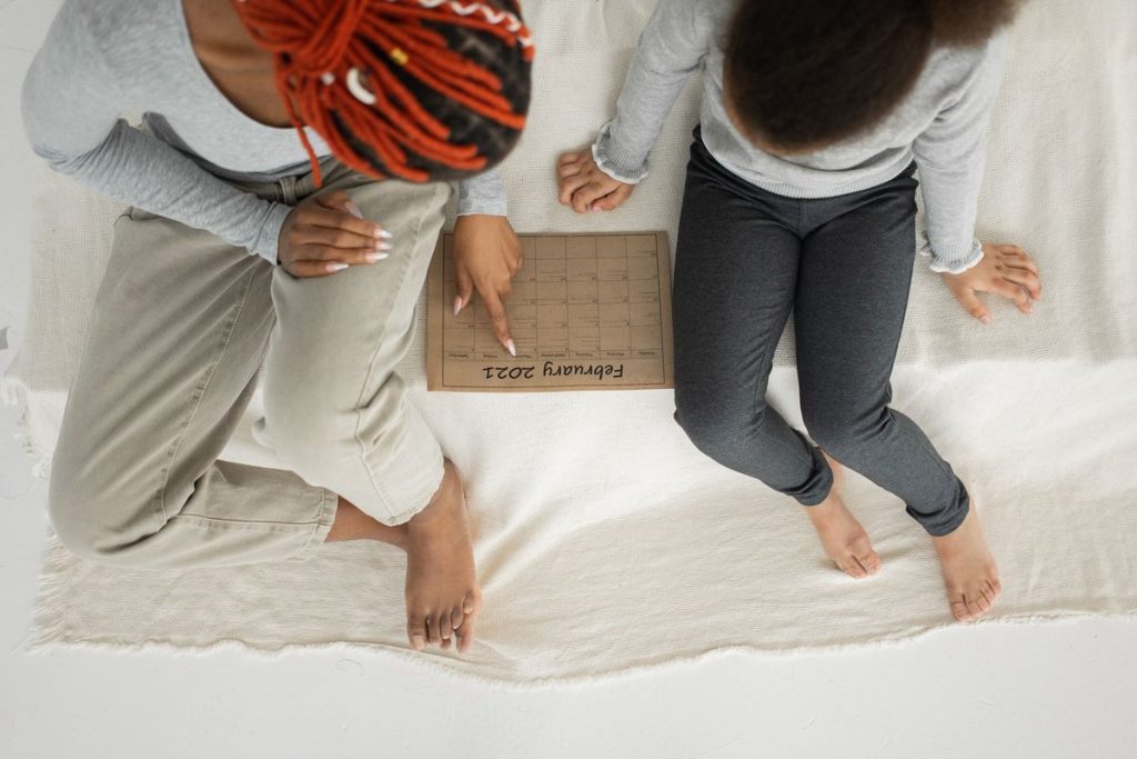 Parent and child tracking dates on a paper calendar